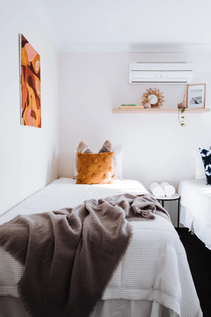 A bedroom with a bed, two pillows and a window.