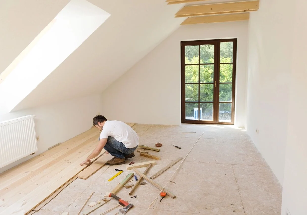 A man is working on the floor of his new home.