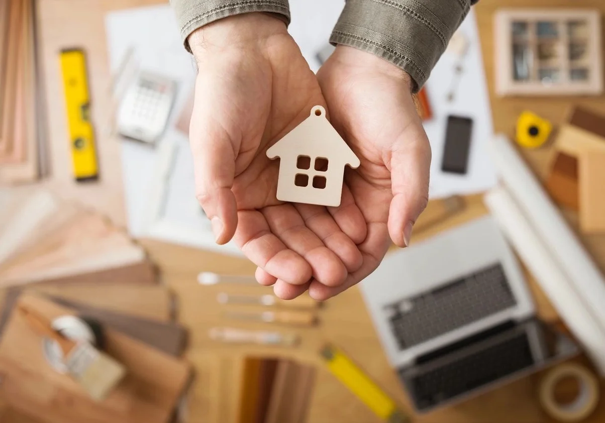 A person holding a small house in their hands.